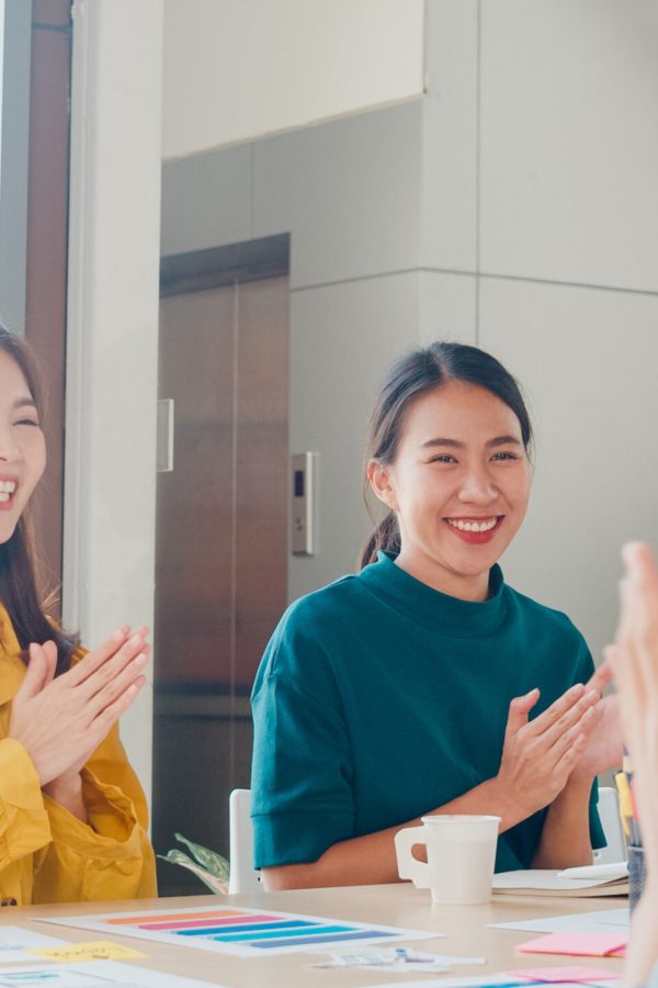 Group of Asia young creative people in smart casual wear discussing business celebrate giving five after dealing feeling happy and signing contract or agreement in office. Coworker teamwork concept.