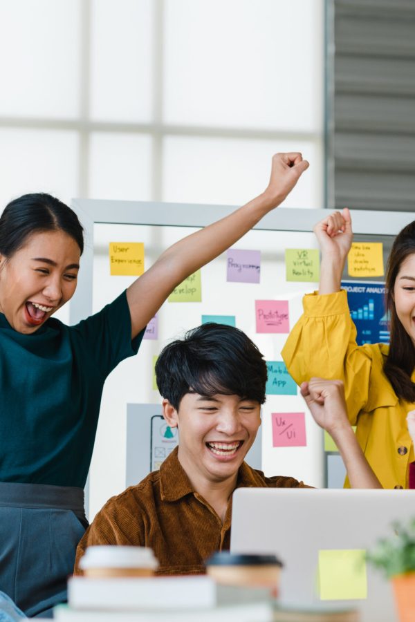 Group of Asia young creative people in smart casual wear discussing business celebrate giving five after dealing feeling happy and signing contract or agreement in office. Coworker teamwork concept.